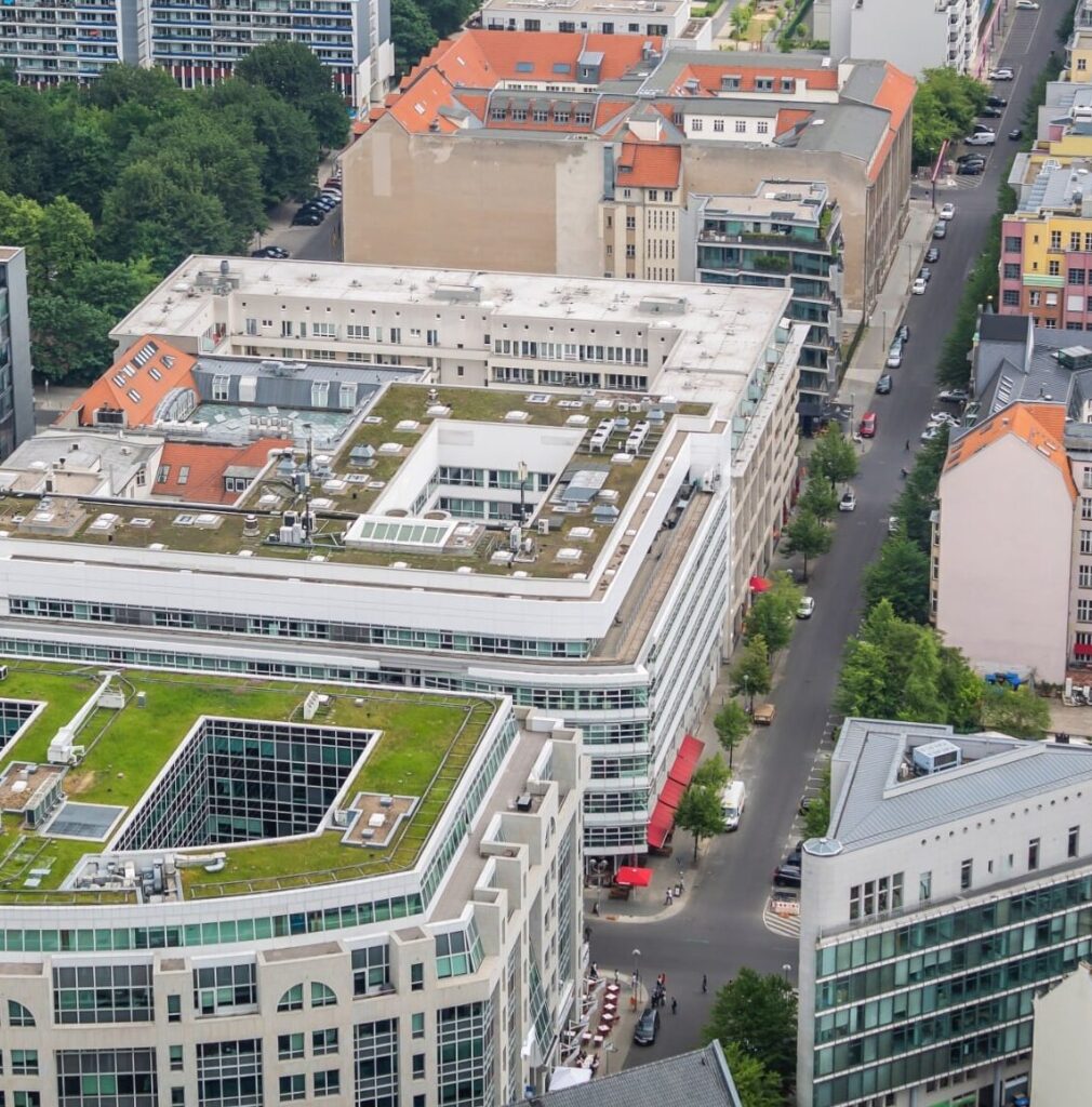 Luftaufnahme einer Innenstadt mit begrünten Dächern und grünen Bäumen